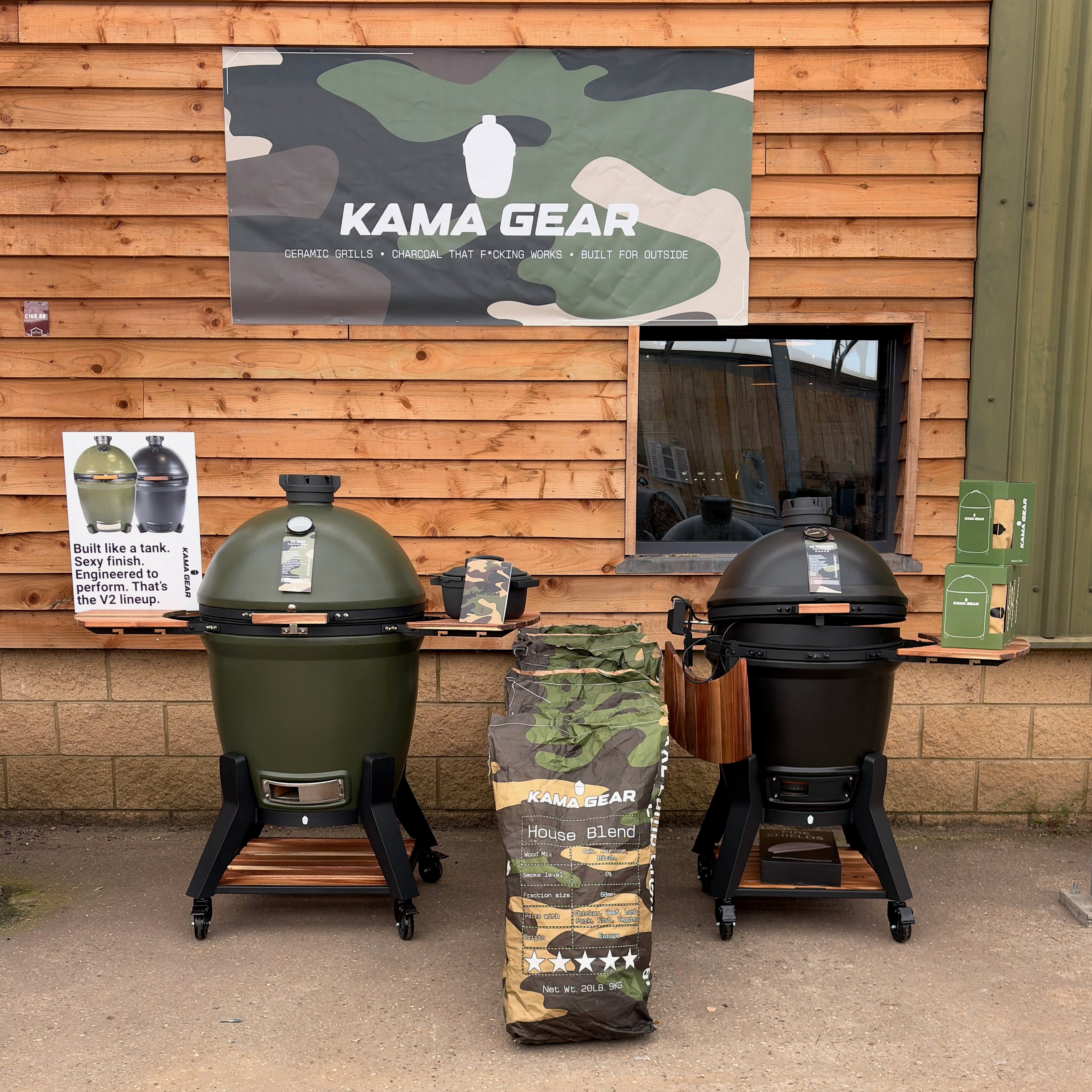 Two smokers on display in front of a wooden building with 'Kama Gear' branding.
