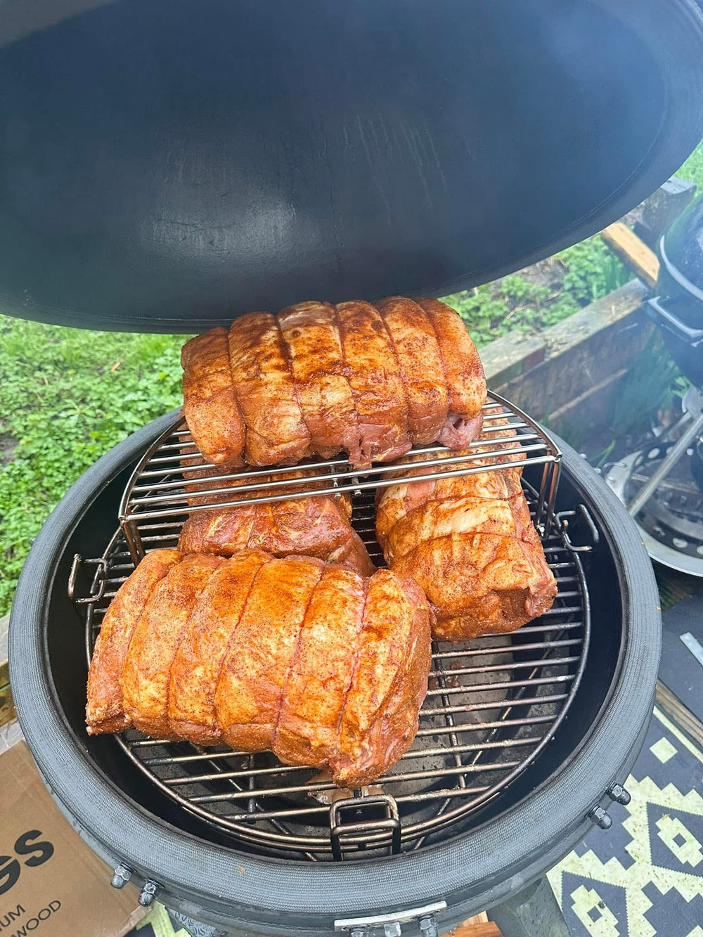 Three rolled roasts cooking at different heights inside an open kamado.