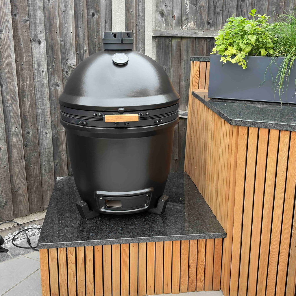 Off-Black KAMA GEAR V2 Kamado installed on a dark worktop in a timber-clad outdoor kitchen.