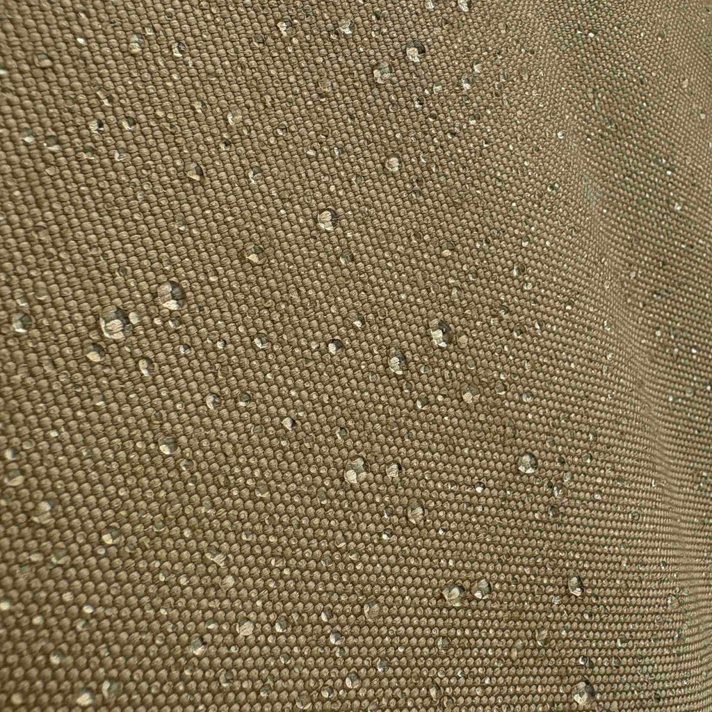 Water droplets beading on the woven surface of a khaki grill cover.