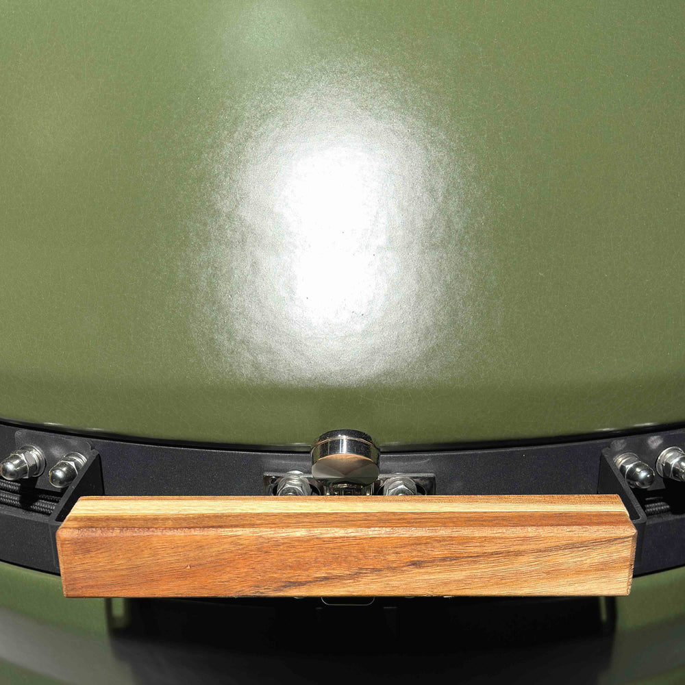 Close-up of the olive-green SmoothShield glaze above the wooden kamado handle.